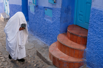Local woman dressed in a white cloak in the city of  Chefchaouen, Morocco.