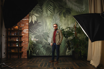 Portrait of young beautiful fashionable man against green wall.