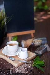 The honey jar and a cup of coffee on a wooden plate with black board background