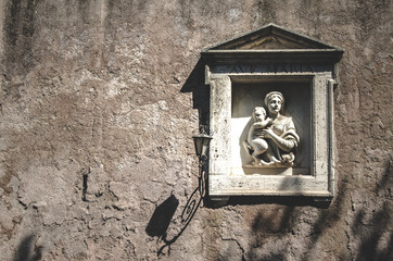 Street sculpture of the Virgin Mary with a baby on one of the walls of Rome. Italy - 342727160