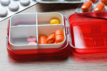 Tablets in a red pill box. Drugs for the treatment of coronavirus. A reminder of taking the pill.