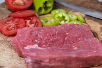 sliced tomatoes, sliced peppers, beef fillet on a wooden background