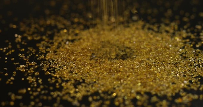 Gold mining, sprinkle fractions of expensive golden metal on black background