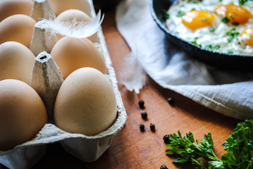 Breakfast, fried eggs in a pan. Chicken eggs are on the table.
