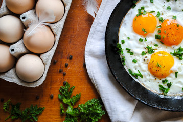 Breakfast, fried eggs in a pan. Chicken eggs are on the table.