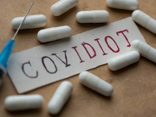 Covidiot Text On Paper, Capsules tablets, Syringe Vaccine, Covid-19 Concept