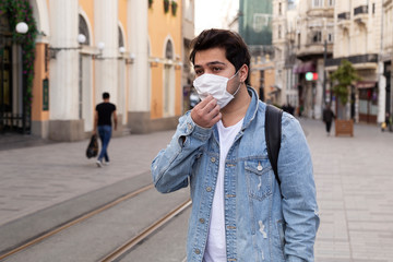Fototapeta premium Young man is walking on the street with a protective mask