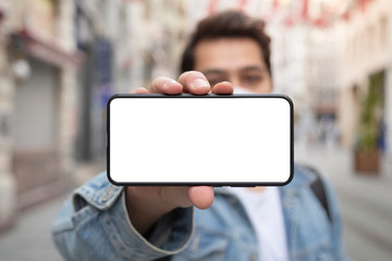 Young man extending his smart phone to the camera