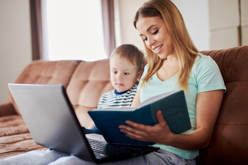 Mother and son drawing in notepad while using laptop