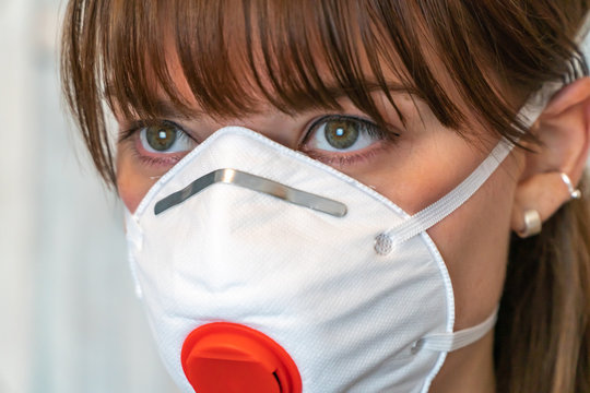 Young brunette woman with N95 respirator medical face mask. Close up of mask and eyes.