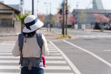 Mother holding a baby waiting at the pedestrian crossing