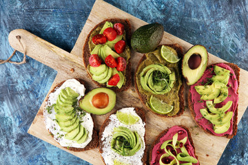 Avocado sandwich. Variation of healthy rye breakfast sandwiches with avocado and toppings like tomato and pomegranate