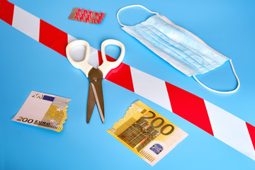 Cut money in euros and a medical mask on a blue background. The concept of problems in the European economy due to the coronavirus epidemic