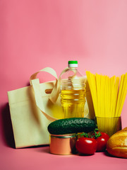 Food supplies crisis food stock for quarantine isolation period on pink. Vermicelli, pasta, canned food, bananas, butter, bread. Food Delivery, Donation, Coronavirus Quarantine.