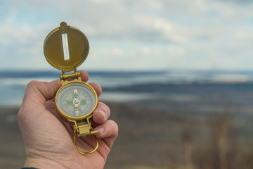 Old gold compass in hand on a background of mountains of nature. Travel concept, camping trip, GPS, orienteering, navigator © gerasimov174