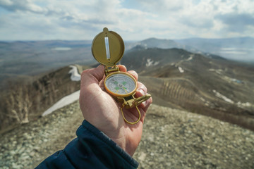 Old gold compass in hand on a background of mountains of nature. Travel concept, camping trip, GPS, orienteering, navigator © gerasimov174