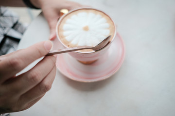 Female hands hold a aromatic beverage, drinks cappuccino or coffee cup, pink cup of cappuccino, hot cappuccino in female hand.