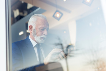Fototapeta premium Senior businessman sending an email using smart phone