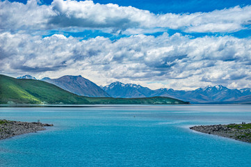 Lake landscape with mountains under cloudy sky