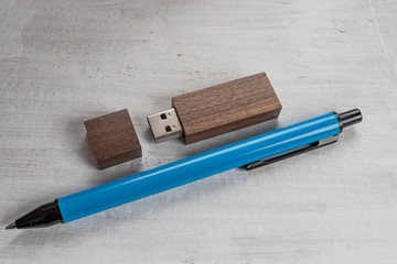 Flash drive and pen on structured gray background.