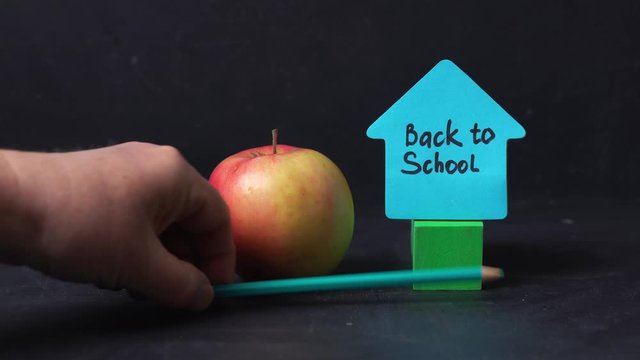 A man rotates an apple with the written formula e = mc2 next to the sticker back to school