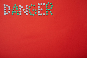Fototapeta premium the inscription danger laid out of tablets on a red background