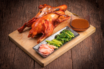 Roast duck on wooden table, Whole roast honey duck with sauce and vegetables served over old wooden table, 