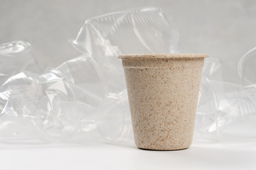 disposable sugarcane cup standing in front of crumpled plastic cups
