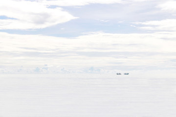 Cloudy white sky and white sea with little black spots of fisherman ships