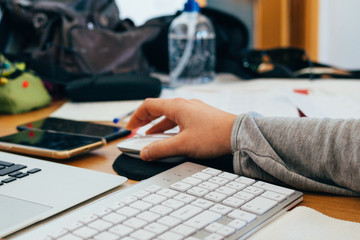 hand moving the computer mouse. Girl working at home with her laptop, calculator and mobile phone