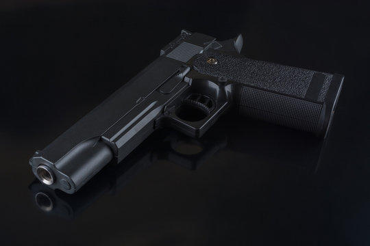 The black gun lies on a black glossy background