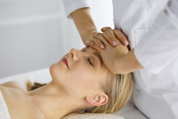 Fototapeta na wymiar Beautiful caucasian woman enjoying facial massage with closed eyes in spa salon. Relaxing treatment in medicine and Beauty concept