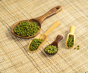 Wooden plate and spoon with green mung beans seen directly from above and isolated on white background