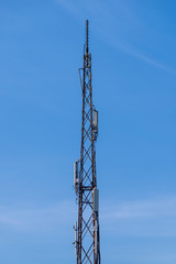 Telecommunication tower with cellular network antenna against blue sky as background