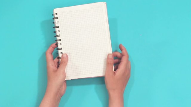 hands holding empty notebook isolated on blue 
