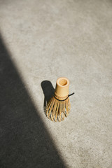 
Matcha bamboo whisk with shadow angle on a gray surface.