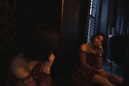 Sexy woman in a red skirt posing outdoors in the park.A bitchy girl smokes a cigarette and catches her eye.Beautiful model in various poses. Summer nature,all in green and red colors.Glasses on a girl