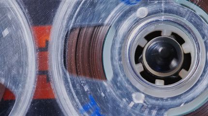 Macro view of a vintage used and worn analog cassette tape playing in a deck.
