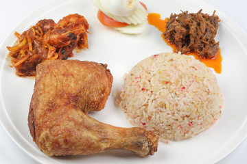 Indonesian royal dish nasi bojari with deep spiced deep fried chicken leg sambal prawn curry beef rendang boild egg cucumber and tomato slice