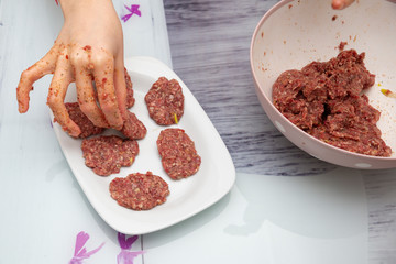 Female hands prepare meatballs on the wooden table