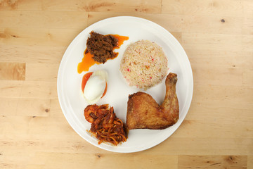 Indonesian royal dish nasi bojari with deep spiced deep fried chicken leg sambal prawn curry beef rendang boild egg cucumber and tomato slice