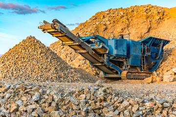 Stone crushing machine in a quarry or outdoor mine - obrazy, fototapety, plakaty