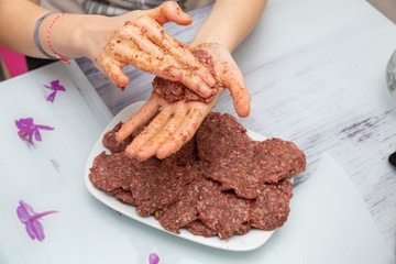 Female hands prepare meatballs on the wooden table