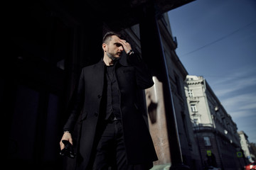 a man in a black suit walks along the historical streets of the city