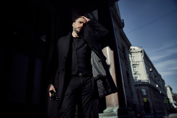 a man in a black suit walks along the historical streets of the city