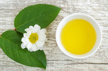Small white bowl with cosmetic oil for natural skin care. Organic cleansing oil, make up remover. Top view, copy space.
