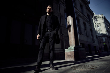 a man in a black suit walks along the historical streets of the city