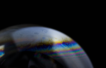 Macrophotography of a soap bubble. Multicolored streaks on the surface of the soap bubble