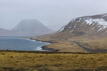 beautiful mountains covered with snow on the ocean in Iceland. Rainy weather