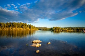 Northern landscape on the lake Kovdozero in the Murmansk region, the village of Zelenoborsky. Northern White Nights in June, beautiful clouds and fir forest